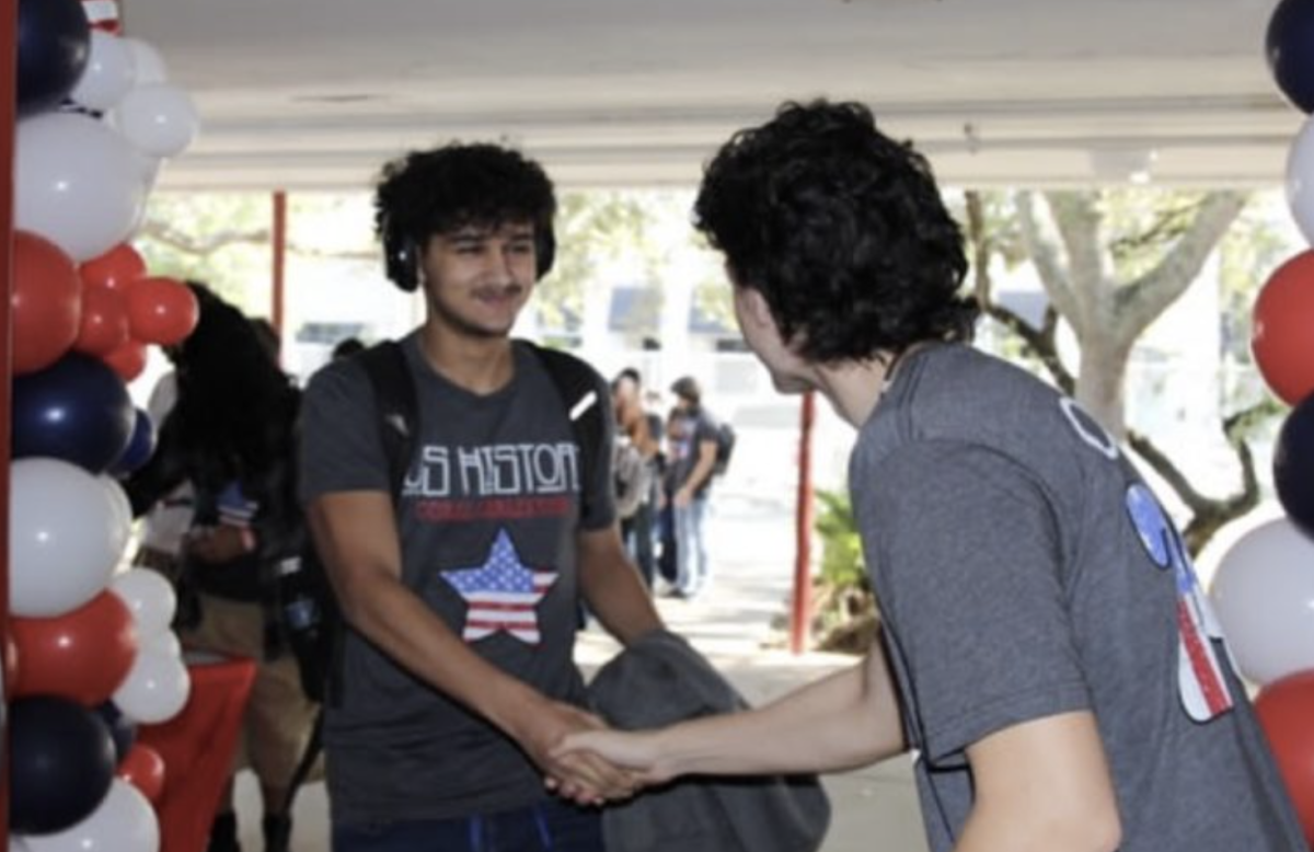 Recibiendo aplausos por aprobar el EOC, ambos estudiantes del último año se dan la mano en un momento de valor antes de entrar al auditorio. 